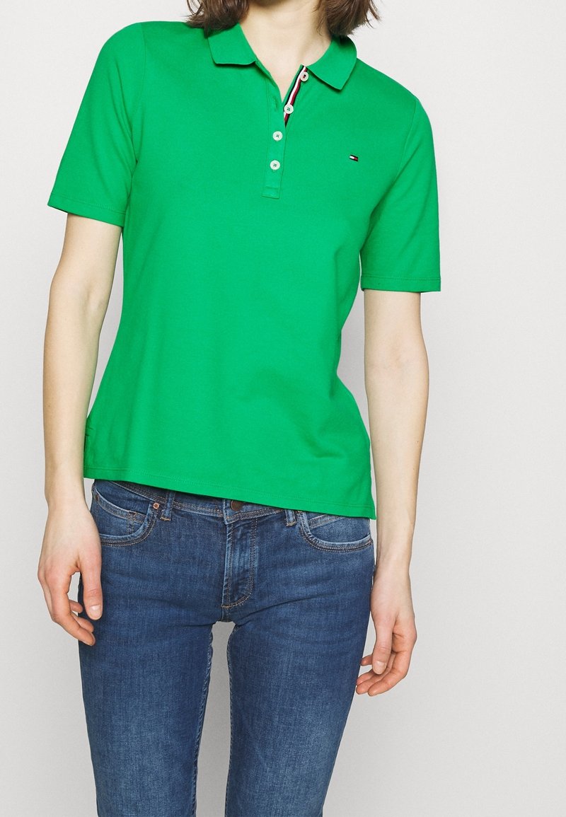 Polo vert en coton, avec col, manches courtes et patte à trois boutons. Détail logo sur le côté gauche.