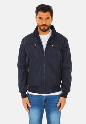 Giacca bomber blu navy in tessuto leggero, con tasche con zip, polsini e orlo a costine, caratterizzata da un collo alto. Texture liscia.