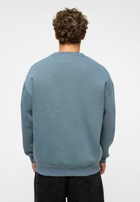 Lichtblauwe sweatshirt met ronde hals en verlaagde schouders, met ribgebreide manchetten en zoom, gemaakt van een zacht materiaal met een gladde textuur.