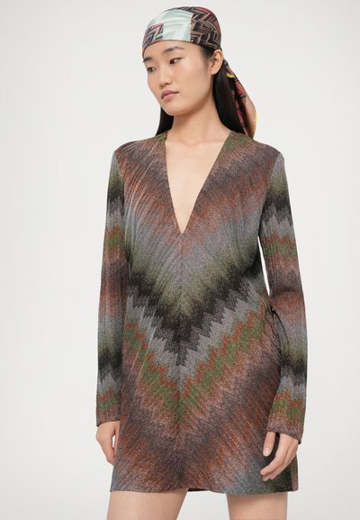 Šaty s dlhým rukávom s hlbokým výstrihom do V, so vzorom cikcak v odtieňoch zelenej, hnedej a sivej, s textúrovaným, trblietavým povrchom.