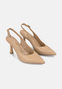 Tacones de piel beige tipo slingback con punta afinada, tacón delgado y correa al tobillo con hebilla circular. Textura suave con un diseño minimalista.