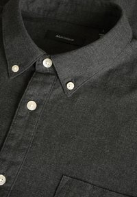 Camisa de botones gris oscuro con cuello estructurado, botones blancos y tela texturizada. Presenta un bolsillo en el pecho y una etiqueta que indica la talla.