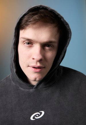 Sweatshirt cinza com capuz, feito de tecido suave, apresentando um logo espiral branco na frente. O capuz está puxado parcialmente para trás.