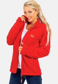 Rote Fleecejacke mit Reißverschluss, seitlichen Taschen und einer weichen, strukturierten Oberfläche. Mit einem Logo auf der linken Brust und einem Stehkragen.