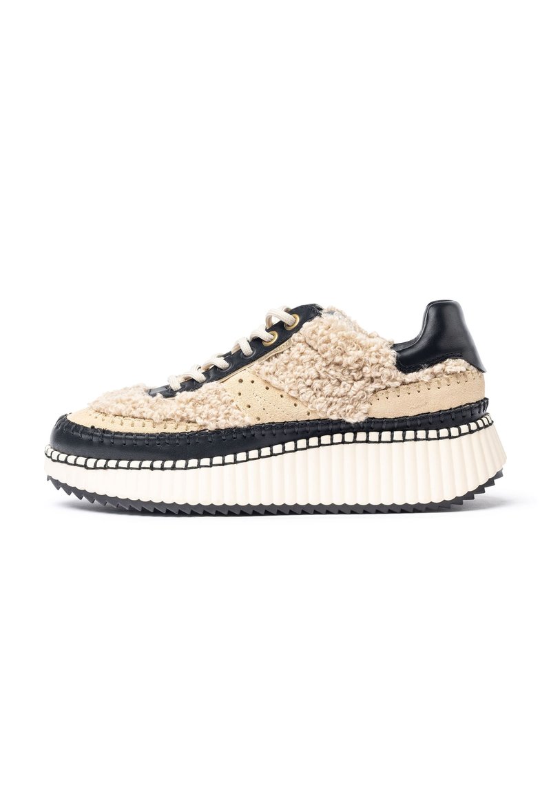 Chunky Sneaker mit einem strukturierten beigen Obermaterial, schwarzen Lederakzenten und einer dicken weißen geriffelten Sohle, die mit kontrastierendem Nähen und Schnüroptik versehen ist.