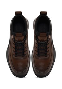 Baskets en cuir marron avec des accents et des lacets noirs. Présente un design épuré et une finition texturée. Semelle plate et boucle de traction au talon.