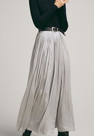 Jupe maxi plissée gris clair à taille haute, associée à une ceinture noire. Le tissu a une texture lisse et un design fluide.