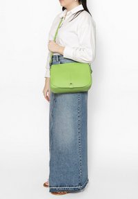 Groene leren schoudertas met een gladde textuur, rechthoekige vorm en een voorflap met een zilveren sluiting.