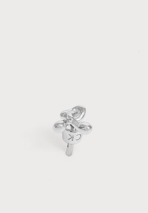 Orecchino a lobo in argento con design astratto attorcigliato e "CK" inciso sul retro su uno sfondo bianco.