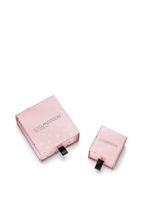 Rožu iepakojuma kastes ar zelta sirdspatērēm, viena lielāka ar melnu lentu un viena mazāka blakus, abām ir zīmola teksts.