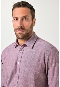 Kortærmet, knappelukket skjorte i en mauve tekstureret stof med en enkelt brystlomme og krave, med hvide knapper.