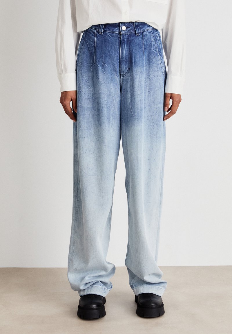 Ανοιχτού μπλε τζιν παντελόνι με φαρδιά γραμμή και κλιμακωτή απόχρωση, με κούμπωμα κουμπιού, εμπρόσθιες τσέπες και χαλαρή εφαρμογή. Ορατή υφή στην επιφάνεια.
