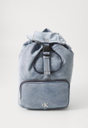 Sac à dos en denim bleu clair. Dispose d'un haut enroulé, d'une fermeture à boucle noire et d'une poche zippée à l'avant avec un logo argenté. Détails cousus tout au long.