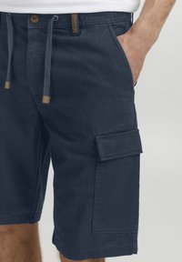 Shorts cargo de marine en tissu durable, avec une taille élastique à cordon, des poches latérales et une poche à rabat sur la jambe.