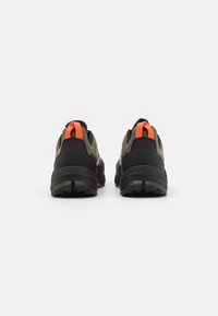 Chaussures de trail running avec une tige noire et olive ornée d'accents orange, semelle texturée et talon rembourré pour le soutien et l'adhérence.