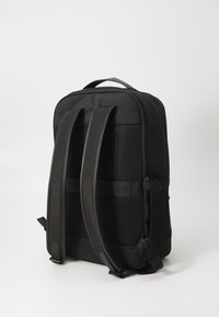 Black backpack featuring mesh panels, padded straps, logo detailing, zippered pockets, and a structured rectangular shape.