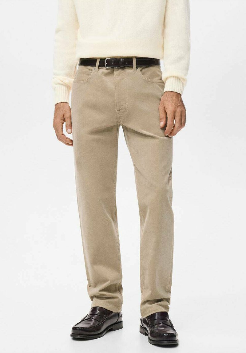 Pantalones de algodón beige con corte recto, bolsillos delanteros y trabillas para cinturón, combinados con mocasines marrón oscuro. Textura suave, detalles mínimos.