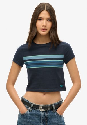 Navy crop t-shirt med korte ærmer, der har vandrette striber i teal og blå på brystet. Sorte denimshorts med en sølvspænde.