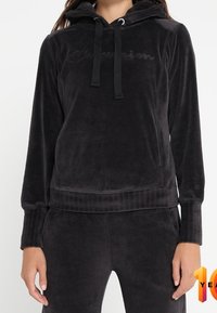 Sudadera de forro polar negro con capucha ajustable, mangas largas, puños de canalé y logo en relieve en la parte frontal. Textura suave y corte relajado.
