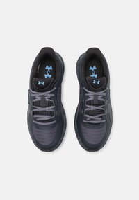 Scarpe sportive grigio scuro con tomaia in mesh e materiale sintetico, lacci grigio chiaro a contrasto e logo blu sulla soletta e sulla linguetta.