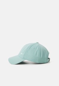 Mint green cap made of cotton blend, featuring a curved brim, embroidered logo, adjustable strap at the back, and stitched ventilation holes.