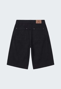 Shorts noirs arrivant aux genoux avec deux poches arrière et un patch en cuir marron portant l'inscription "PXP" sur la ceinture.