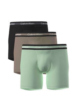 Drei Paar Herren-Boxershorts in Schwarz, Braun und Hellgrün, jeweils mit einem Calvin Klein Markenbund.