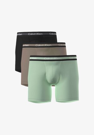Trois paires de boxers pour hommes en noir, marron et vert clair, chacun avec une ceinture de marque Calvin Klein.