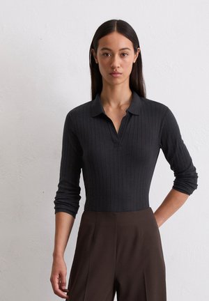 Zwarte geribde long-sleeve polo met een kraaghalslijn, een getailleerd silhouet en een zachte textuur, gecombineerd met bruine high-waisted broeken.