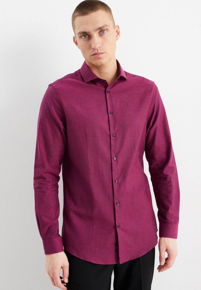Langarmshirt in een diepe magenta stof, met een normale kraag, een knoopsluiting aan de voorkant met donkere knopen en een gladde textuur.