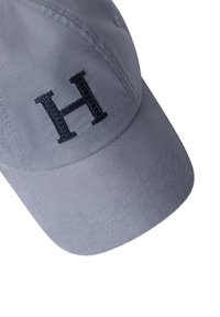 Gorra de béisbol gris claro con la letra "H" bordada en negro en el panel frontal, detalles visibles de costura en la visera y la corona.