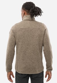 Veste en polaire beige avec col montant, tissu texturé et coupe slim. Dotée d'un empiècement au dos et d'une conception d'épaule sans coutures.