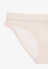 Slip in pizzo rosa chiaro con vita liscia, caratterizzato da un motivo floreale e un tessuto semi-trasparente, che conferisce un aspetto delicato.