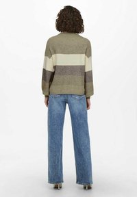 Knitted sweater in olive green, cream, and brown stripes; loose fit with long sleeves, paired with light blue high-waisted jeans.