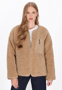Beige, fuzzy Fleecejacke mit Reißverschluss, rundem Halsausschnitt und einer strukturierten Tasche auf der linken Brust. Lange Ärmel und lässige Passform.