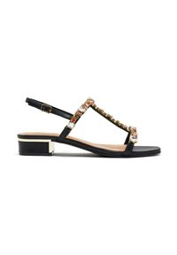 Sandalia de cuero negra con diseño de tira en T, adornada con acentos de oro y cristales, y un tacón bajo, con una correa en el tobillo que se cierra con hebilla.