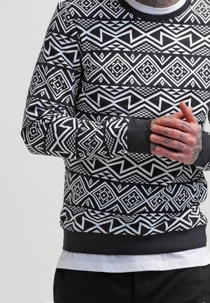 Svart och vit mönstrad sweatshirt med geometriska designs, rund halsringning, långa ärmar samt ribbade muddar och nederkant.
