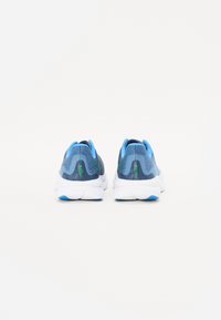 Baskets de sport avec une tige en mesh texturé bleu et gris, col rembourré et semelle blanche avec des accents bleus. Design lisse avec un matériel minimal.