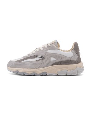 Zapatilla deportiva en gris claro y beige con paneles de ante y malla, cierre de cordones y suela gruesa sobre un fondo blanco.