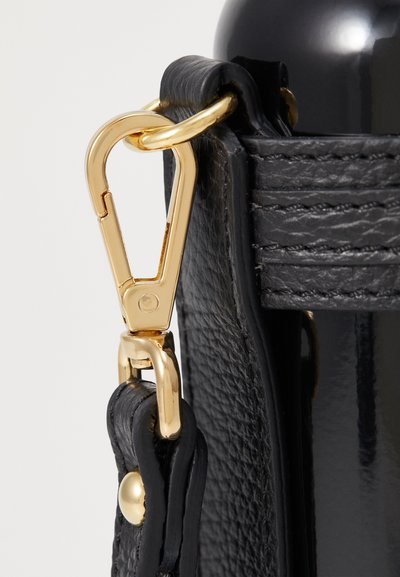 Bracelet en cuir noir avec une pince en métal doré. Le bracelet présente une couture texturée et une finition lisse près du point d'attache.