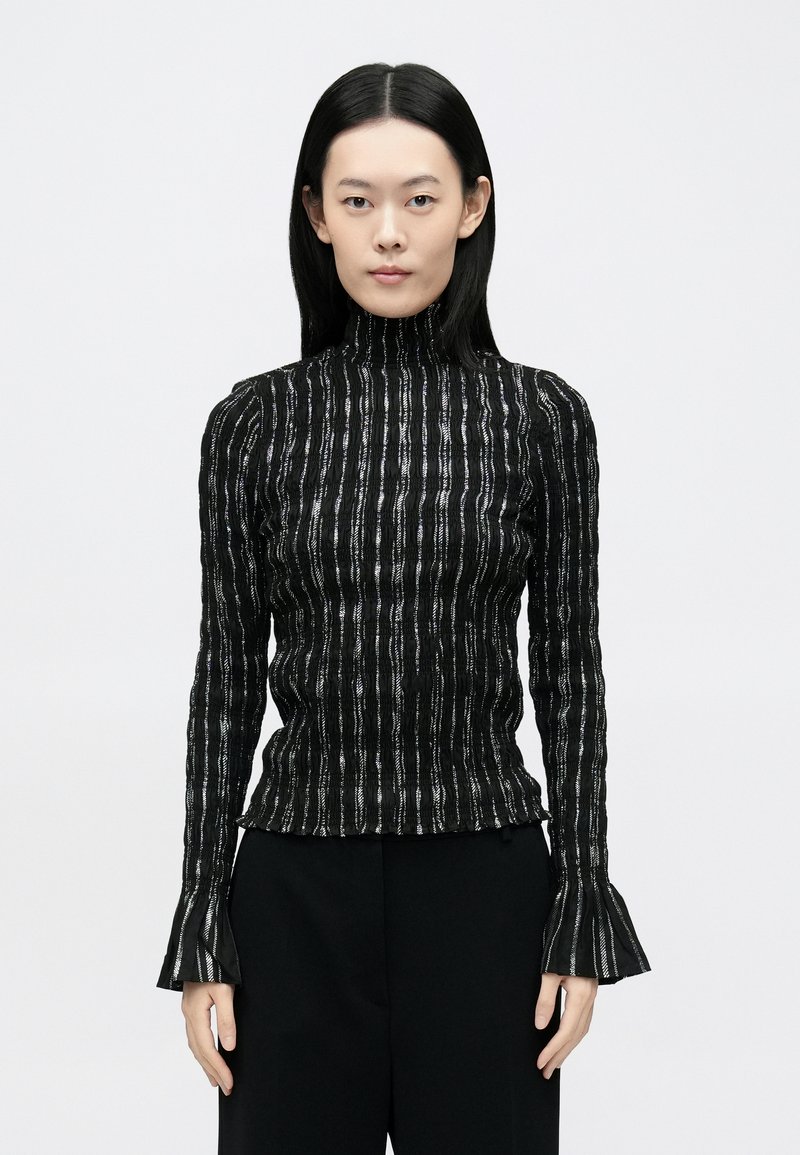 Bluză neagră cu mâneci lungi și guler înalt, cu dungi verticale texturate și manșete evazate. Material moale cu accente metalice.