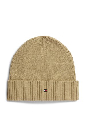 Beige knitted beanie hat with folded ribbed cuff and small rectangular red, white, and navy logo on front center of cuff.