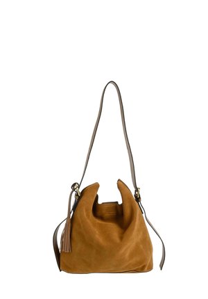 Sac épaule en daim marron avec bandoulière longue réglable et détail pompon sur le côté, forme souple et décontractée, sur fond blanc.