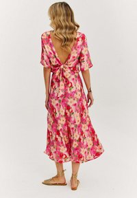 Maxi šaty s květinovým potiskem v odstínech růžové a zelené, s V výstřihem na zádech, krátkými rukávy a detaily v pase na zavazování. Plynulá textilní struktura.