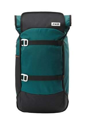 Teal und schwarzer Rolltop-Rucksack mit zwei horizontalen schwarzen Gurten und weißen Schnallen, mit einem kleinen weißen Logo-Patch auf der oberen Klappe.