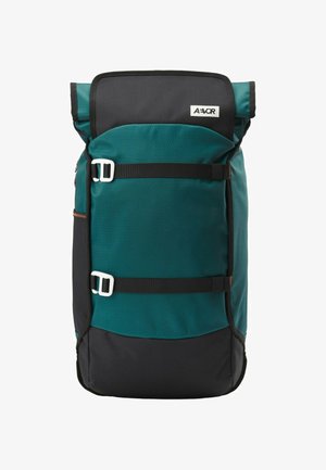 Teal und schwarzer Rolltop-Rucksack mit zwei horizontalen schwarzen Gurten und weißen Schnallen, mit einem kleinen weißen Logo-Patch auf der oberen Klappe.
