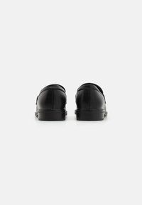 Black leather shoes with a smooth finish, rounded toe, low heel, and subtle stitching details. Back view shows a clean, minimal design.