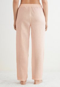 Ljusrosa, löst sittande byxor med elastisk midja; tillverkade av textil med struktur; heldragna med raka ben, utan synliga mönster.