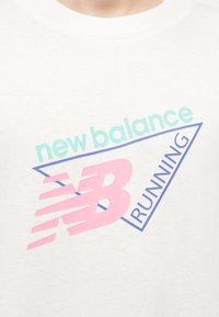 Λευκό πουκάμισο με παστέλ κείμενο «new balance» σε τιρκουάζ, μεγάλο ροζ λογότυπο «NB» και μπλε «RUNNING» μέσα σε τριγωνικό περίγραμμα.