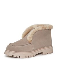 Bottine en daim beige avec doublure en shearling, bout rond et semelle en caoutchouc épaisse et crantée. Présente un revers rabattable pour une hauteur réglable.